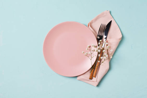 istock Tableware setting with fork, knife, napkin and flower on blue background, 1313299988