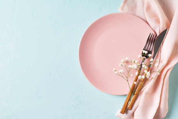 istock Tableware setting with fork, knife, napkin and flower on blue background, 1313299995