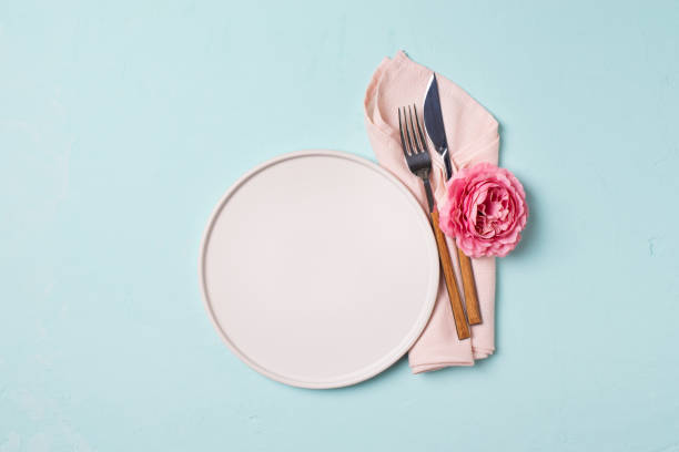 istock Tableware setting with fork, knife, napkin and flower on blue background, 1313300000