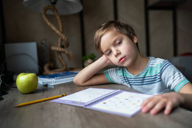 istock Little boy is tired of doing homework 1313300051