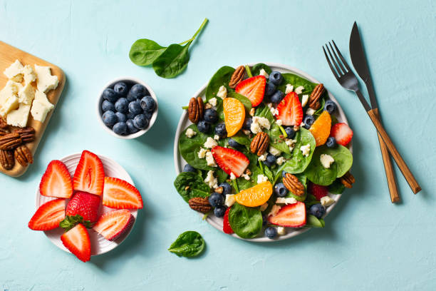 istock Summer salad with berries, cheese and spinach on blue background 1313300060