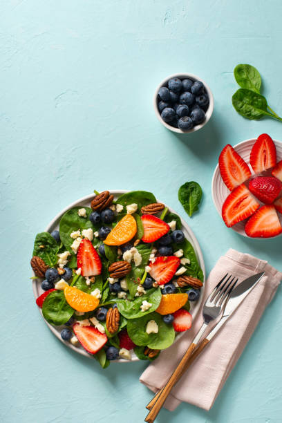 istock Summer salad with berries, cheese and spinach on blue background 1313300062
