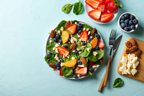 istock Summer salad with berries, cheese and spinach on blue background 1313300065