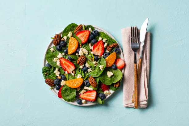 istock Summer salad with berries, cheese and spinach on blue background 1313300067