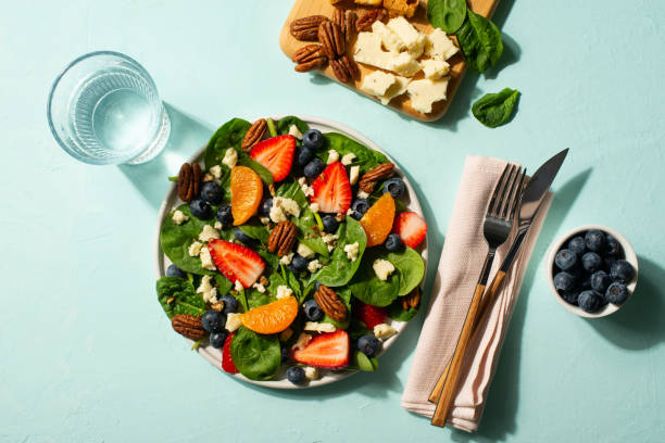 istock Summer salad with berries, cheese and spinach on blue background 1313300070