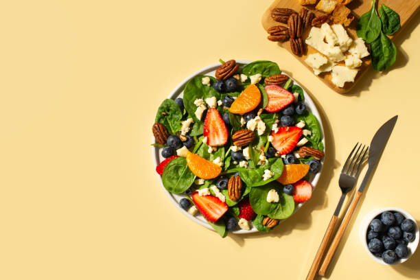 istock Summer salad with berries, cheese and spinach on yellow background 1313300071