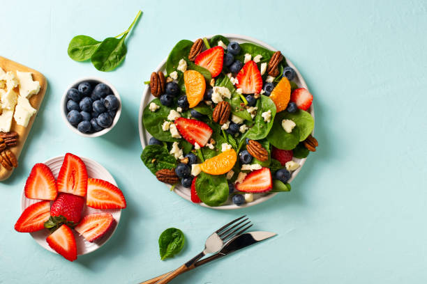 istock Summer salad with berries, cheese and spinach on blue background 1313300074