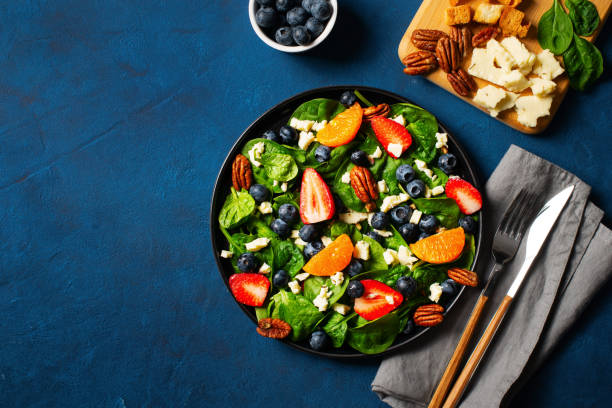 istock Summer salad with berries, cheese and spinach on blue background 1313300079
