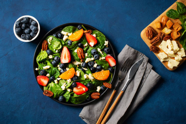 istock Summer salad with berries, cheese and spinach on blue background 1313300080