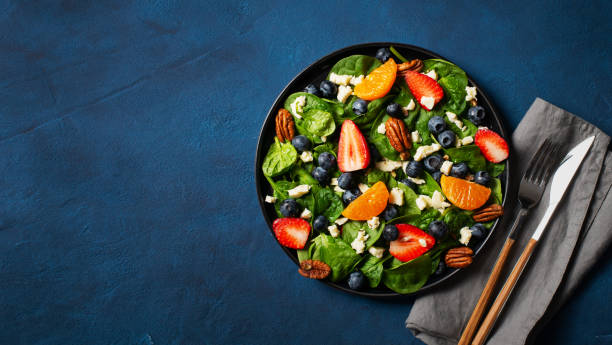 istock Summer salad with berries, cheese and spinach on blue background 1313300081