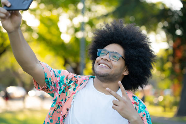 istock Latin man taking a selfie with phone outdoors. 1313302108