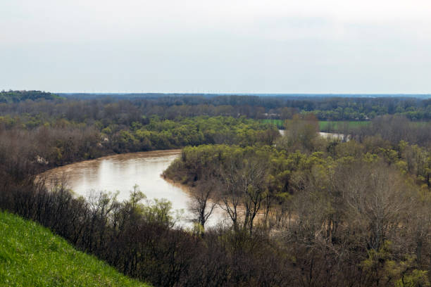 istock Panoramic view from the high bank to the river, forest, green meadow and beautiful fields. View from the high bank to the spring river and the trees around. 1313304384