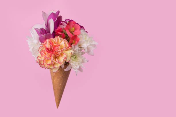 istock Ice cream cone with many different colorful flowers on a pastel pink background. 1313304877