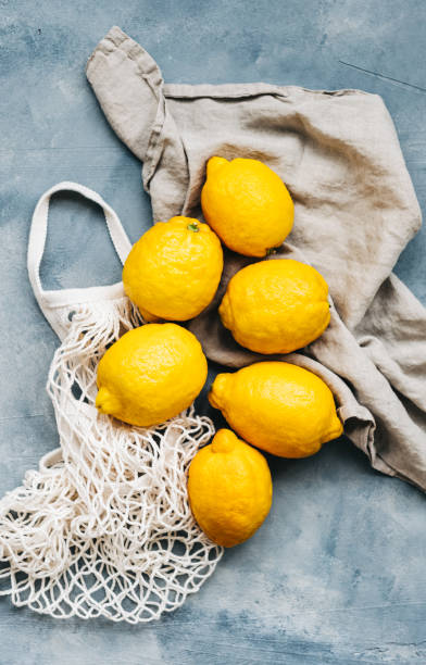 istock Fresh lemons on eco net bag with linen fabric, top view. 1313307008
