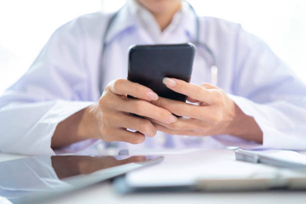 istock Female doctor hands holding and using mobile smart phone with laptop computer and stethoscope on the table 1313309669