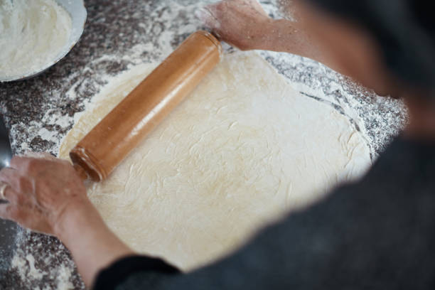istock Making traditional baklava at home. Old woman rolling dough with rolling pin on kitchen counter 1313310043