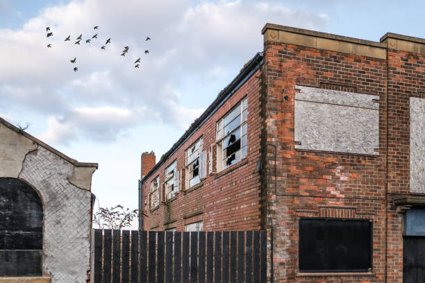 verlassene heruntergekommene industriegebäude zerbrochene fenster leer und beschädigt. rote backsteinbauvögel fliegen in den himmel hinter vandalisierten schäbigen verlassenen verlassenen haus. - house abandoned run down broken stock-fotos und bilder