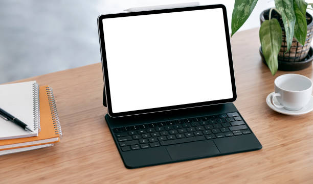istock Mockup blank screen tablet, coffee cup and notebook on wooden table. 1313311866
