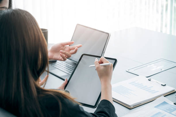 istock young businesswoman holding digital pen pointing on tablet screen while working with her team in modern office. 1313312510