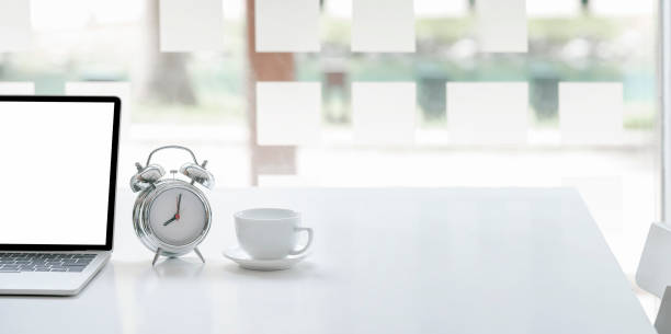 istock Cropped image for background with tablet and keyboard, alarm clock and coffee cup on white table. 1313312616