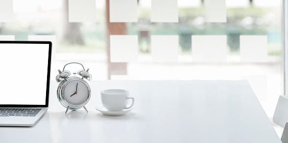 Cropped image for background with tablet and keyboard, alarm clock and coffee cup on white table, copy space.