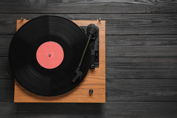 istock Turntable with vinyl record on black wooden background, top view. Space for text 1313313774