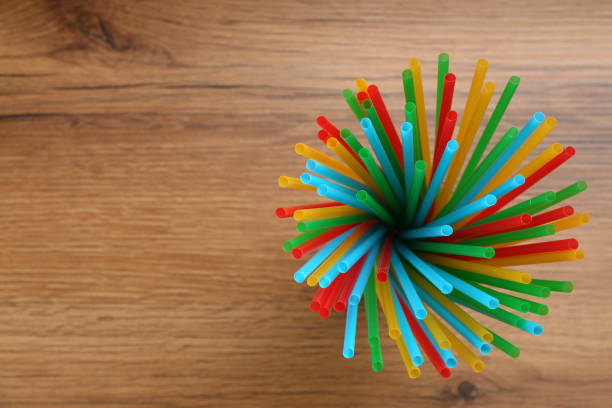 istock Colorful plastic drinking straws on wooden table, top view. Space for text 1313313789