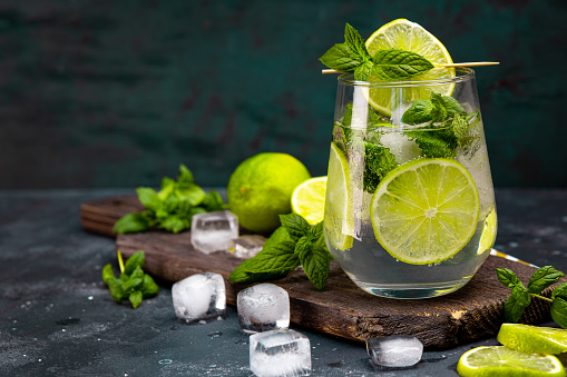 Refreshing mojito with lime, mint and ice in a glass on a dark background, free space for text. Cold summer cocktail. High quality photo