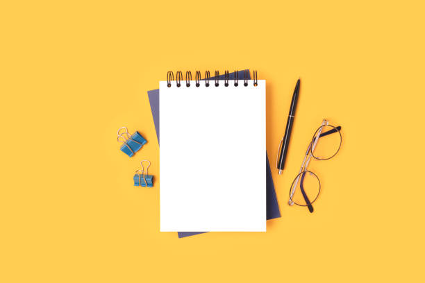 istock Workspace with notepad mockup, eyeglasses and stationery on a yellow background. 1313316434