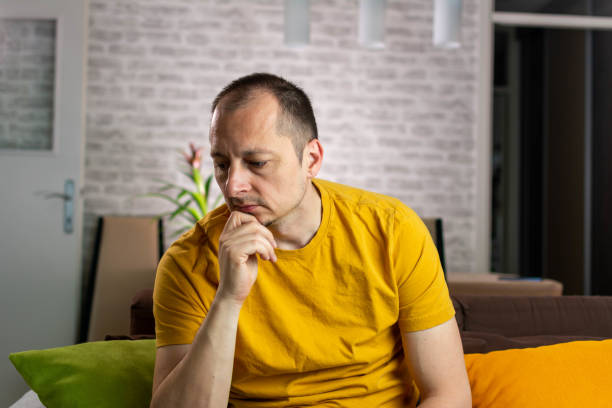 People unhappy and strain Unhappy depressed caucasian male sitting and lying in living room couch feeling desperate a lonely suffering from depression. Unpleasant pain. low photos stock pictures, royalty-free photos & images