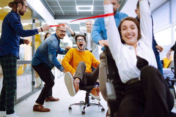 istock Friendly work team  ride chairs in office room cheerfully excited diverse employees laugh while enjoying fun work break activities, creative friendly workers play a game together. 1313318154