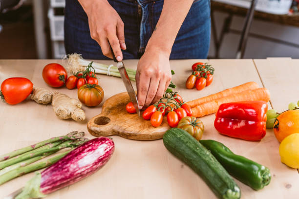istock hand chopping tomato cherry preparing spring lunch in kitchen with fresh vegetables. concept of spring diet and organic vegan nutrition 1313318354