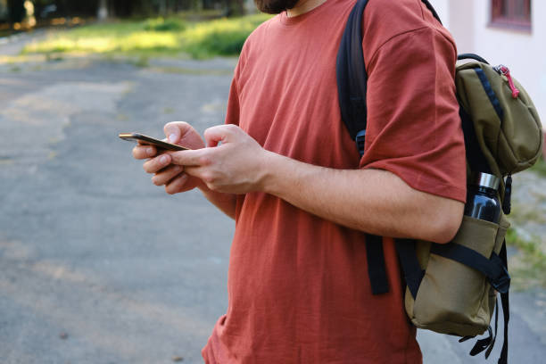 istock A man with a backpack holds a smartphone in his hands. A traveler with a mobile pass browsing the Internet or reading e-mail. Modern technologies in life. Navigating by phone 1313318380