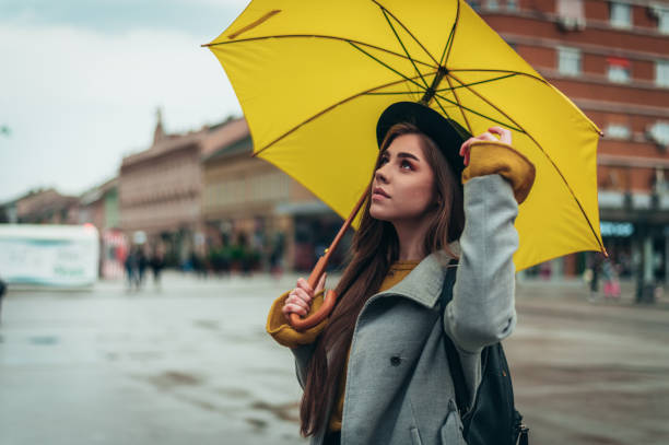 istock Woman holding a yellow umbrella while walking on a rainy day 1313319721