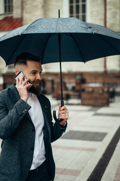istock Businessman holding a black umbrella and using a smartphone 1313319729