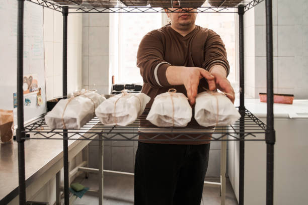 istock Male worker putting packing cakes on a bakery trolley 1313320741