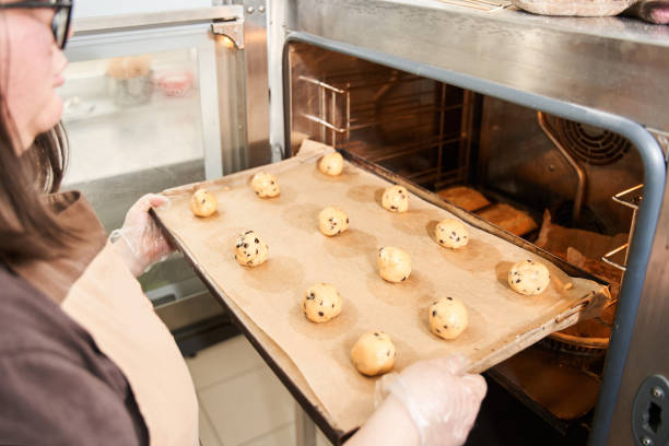 istock Baker putting tray with balls from the dough to the oven 1313320770