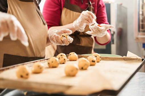 Favourite work. Close up view of the two female bakers sculpting balls from the dough for the future cookies. Coolinary concept. Stock photo