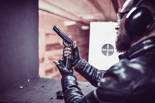 Bearded Male Focused On Putting Magazine In Gun And Loading It