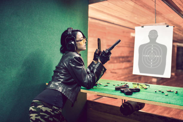 istock Beautiful Female Wondering How To Load Handgun Before Shooting On Target 1313321192
