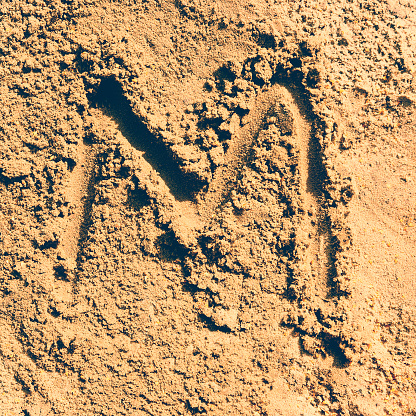 alphabet letter ''M'' made from sand