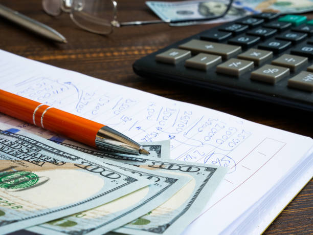 istock Financial calculations written by hand in a notebook, dollars and a calculator. 1313323854