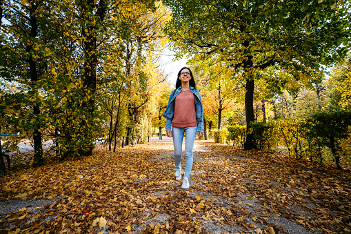 Young cute Caucasian woman walking in a park in Vienna. Autumn time.