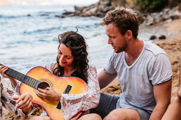 istock Friends playing guitar and singing on beach 1313325029