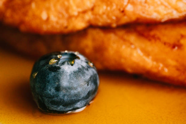 A blueberry with honey drips on a plate of fried bread