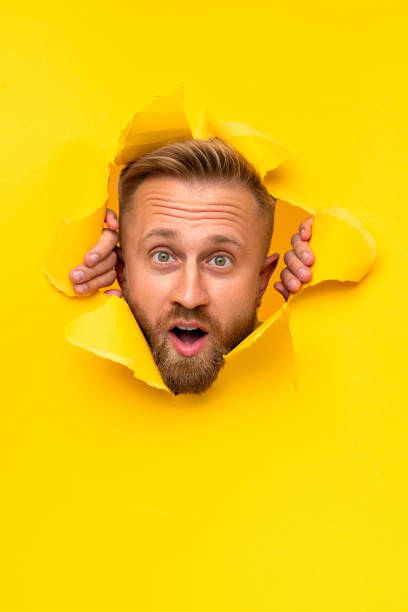 istock Surprised male tearing yellow paper 1313331010