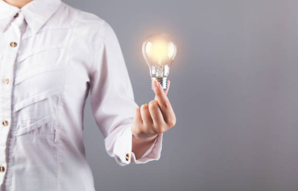 istock Woman hand holding a bulb. On a gray background. 1313331179