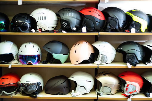 Large selection snowboard and ski helmets on a rack in a sports equipment store
