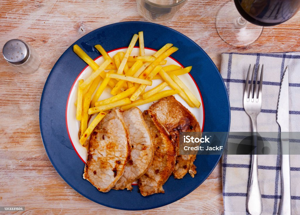 Fried barbecue pork meat with baked potato Roasted pork loin Lomo de cerdo con patata with potatoes fries on a ceramic plate cooked in a cafe Barbecue - Meal Stock Photo