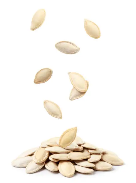 Pumpkin seeds not peeled fall on a heap close-up on a white background. Isolated